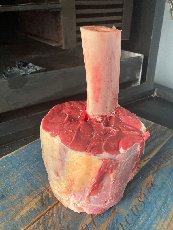 A Beef Shank Thor's Hammer (1lb) sitting on top of a wooden table, available for purchase from We Speak Meat Company.